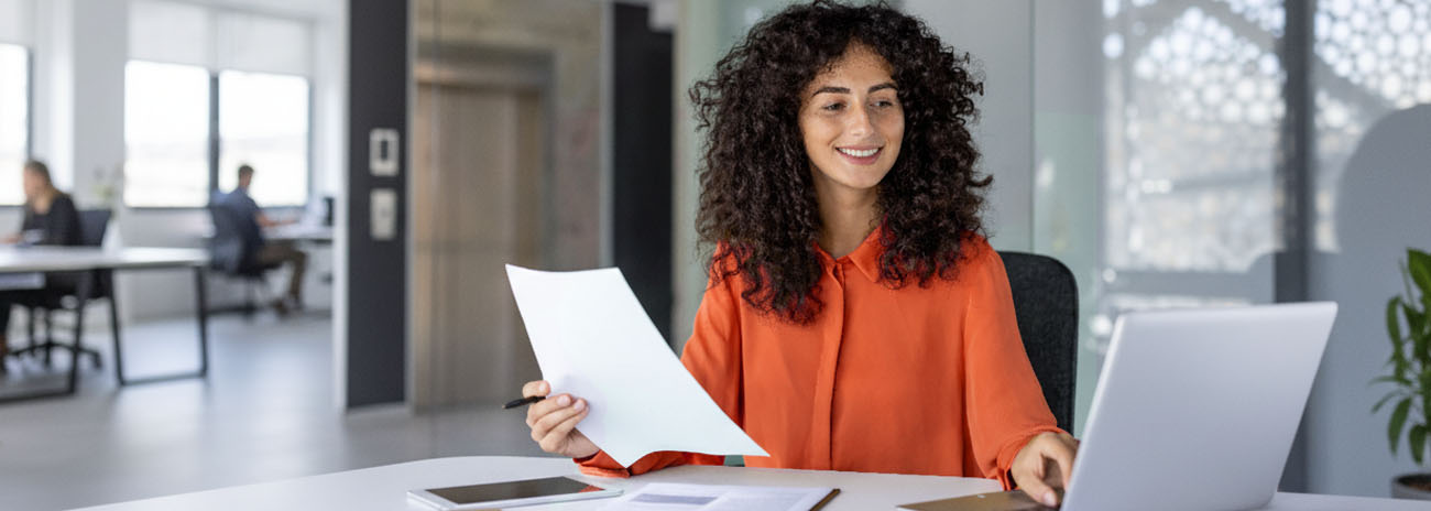 Woman preparing tax and compliance paperwork on a laptop