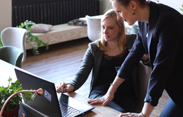 two woman discussing in front of a computer